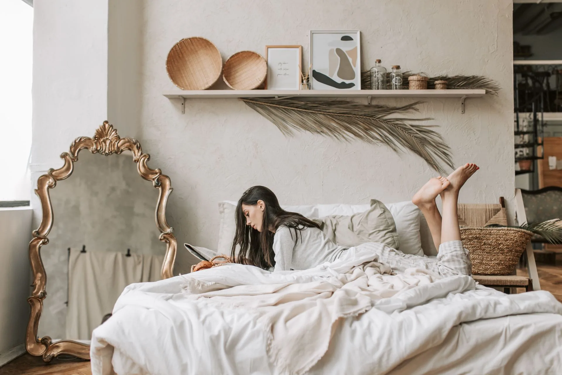 Ambiente decorado com luz natural quente, tapete, espelho dourado e cama arrumada
